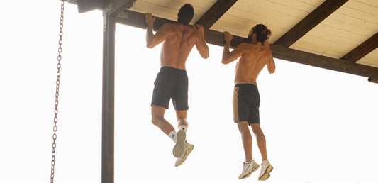 dos hombres haciendo dominadas en una viga de madera