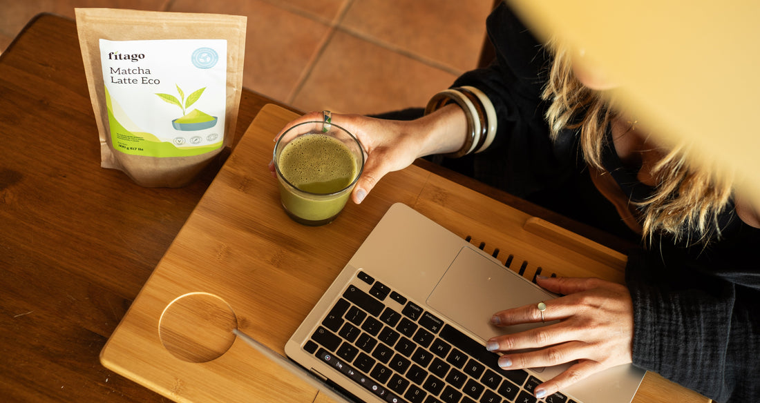 Foto de paquete de matcha latte de Fitago y chica bebiendo té matcha mientras trabaja con un ordenador portátil